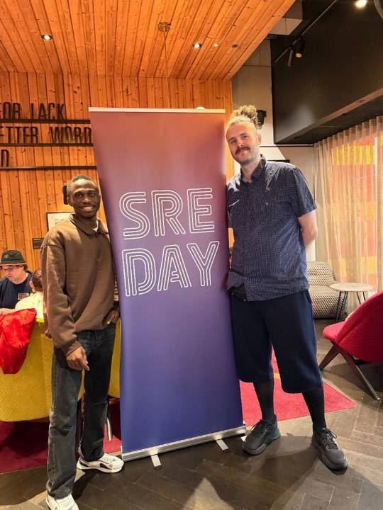 Gabriel with another attendee beside the SRE Day banner